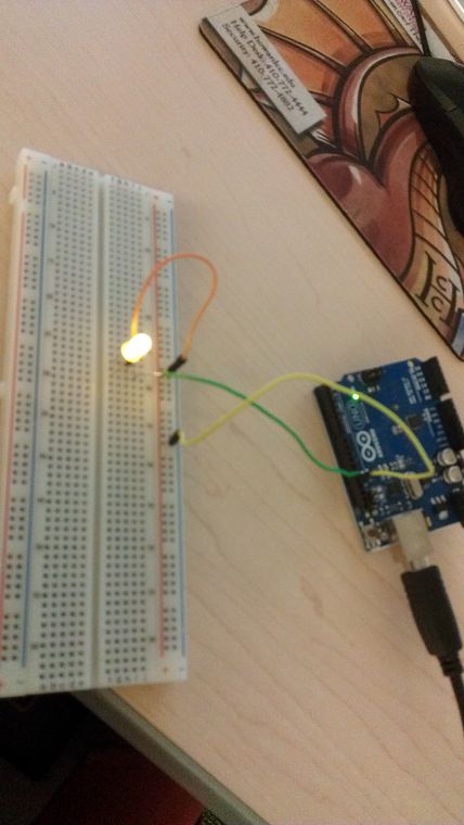 An Arduino with a single LED plugged into its header, lit