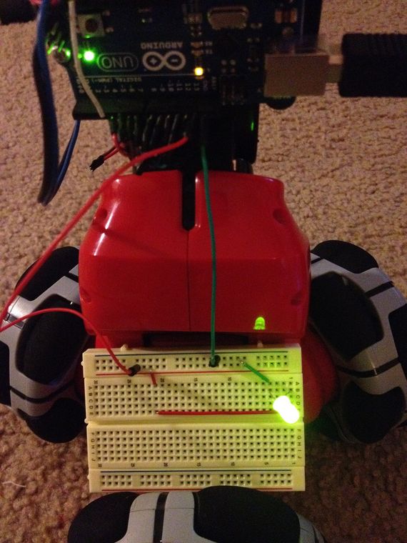 A breadboard wired to an Arduino with jumper wires, a resistor and a lit LED