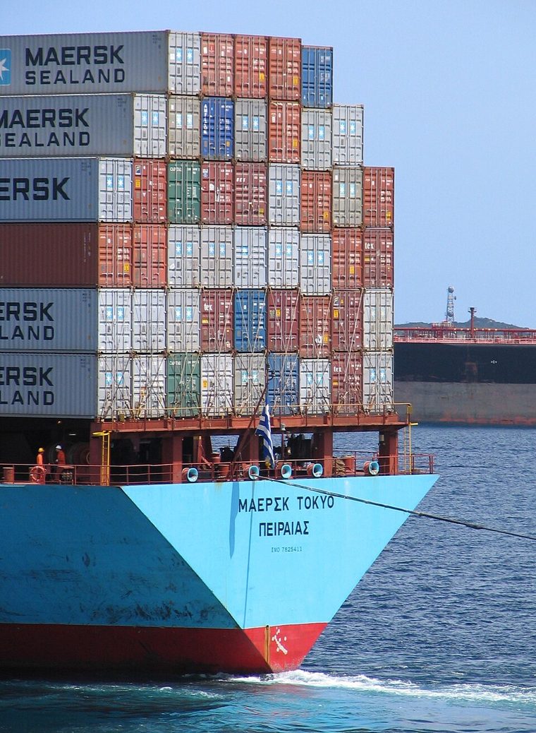 The bow of the blue container ship Maersk Tokyo, stacked high with containers, under way on blue water