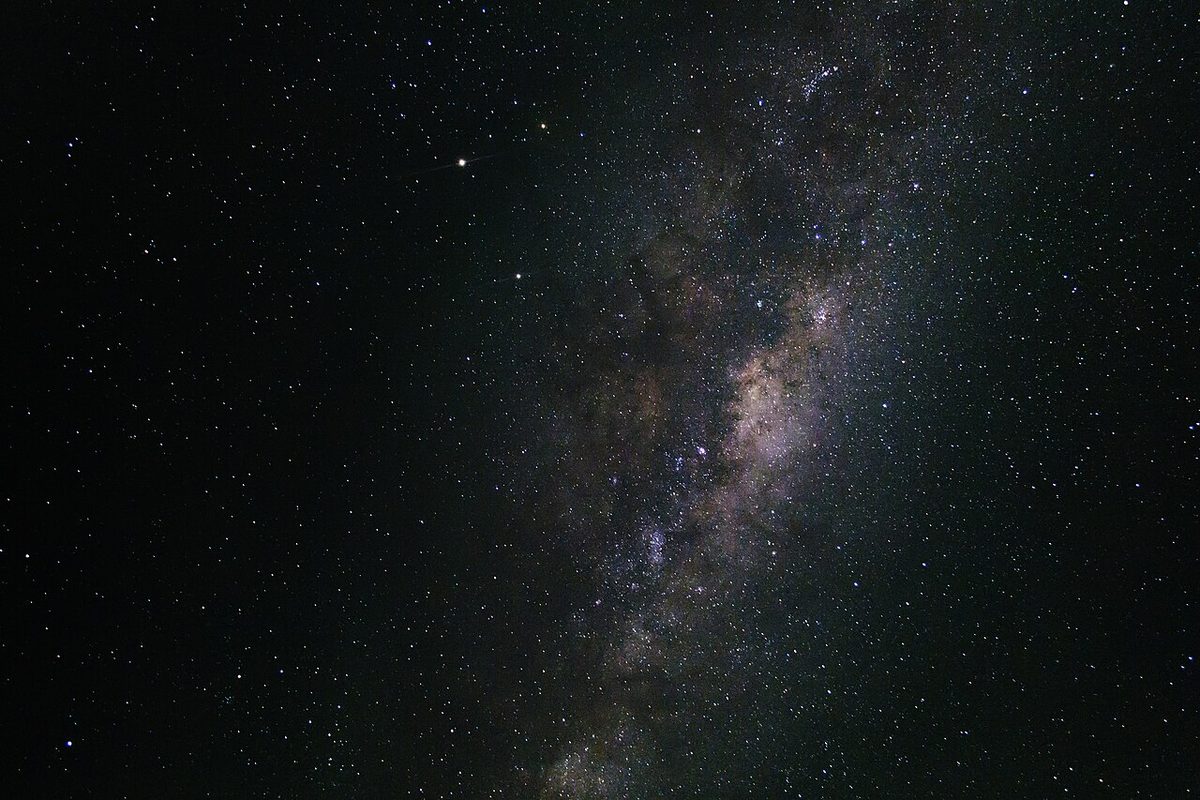 The Milky Way as a pale band of stars and dark dust across a black night sky