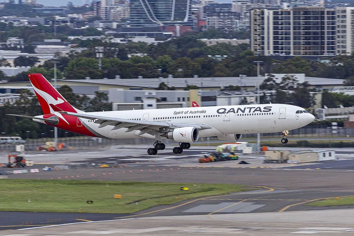 A white Qantas Airbus A330 with a red tail, wheels down, just above the runway at Sydney Airport