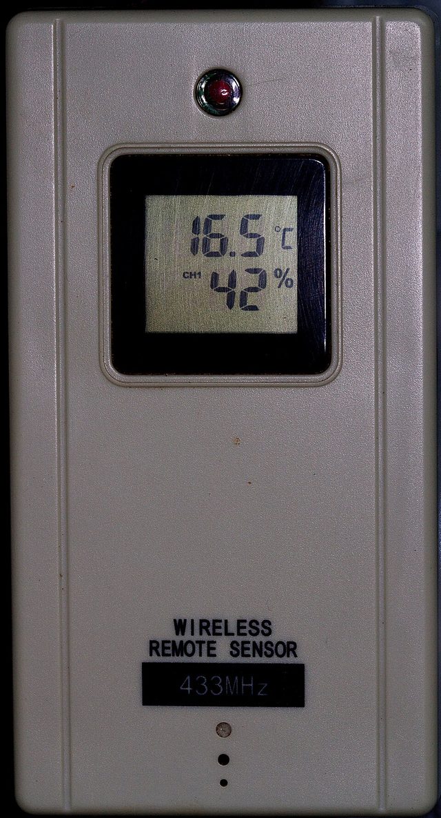 A beige outdoor weather sensor with a small screen showing 16.5 degrees and 42 per cent humidity, labelled Wireless Remote Sensor 433 MHz