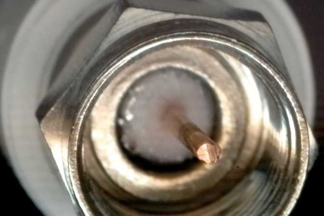 An F-type plug seen end-on, with the cable's copper core as its pin