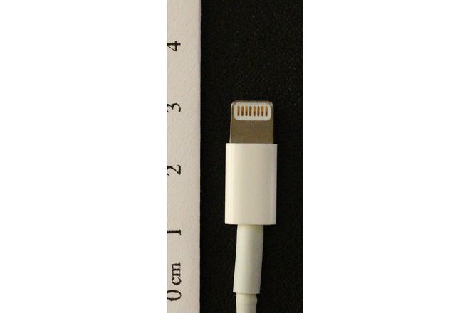 An Apple Lightning plug beside a ruler