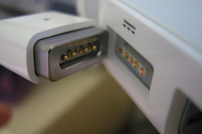 An original MagSafe plug next to the MagSafe port on a MacBook