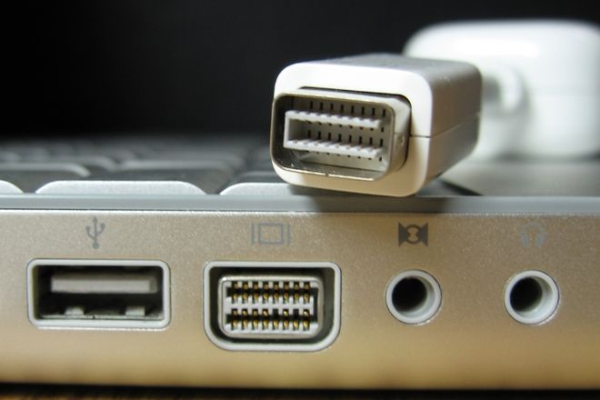 A Mini-DVI plug held above the Mini-DVI port on a MacBook