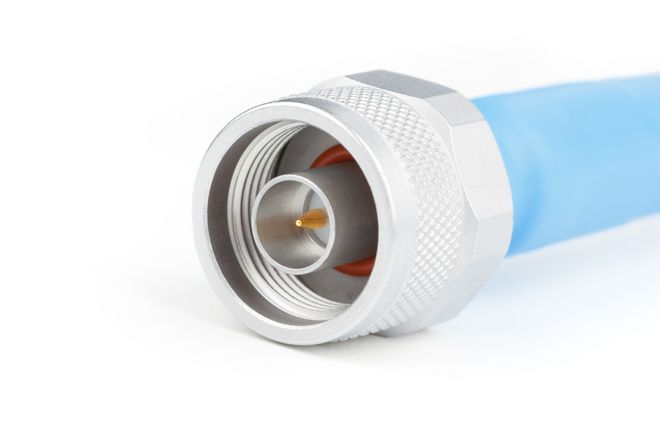 An N-type plug on a cable: a knurled coupling nut around a metal sleeve, white insulator and gold centre pin