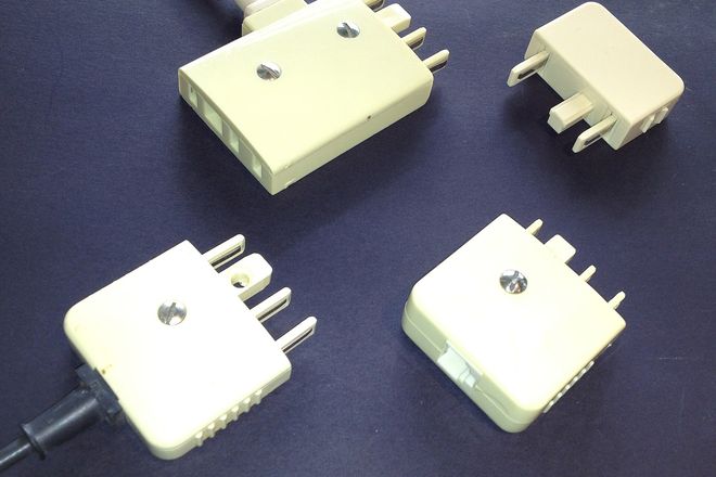 Four cream Australian 600-series telephone plugs and adapters, showing their flat pins