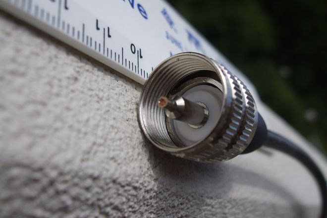 A PL-259 plug beside a ruler: a knurled shell around a white insulator and a thick centre pin