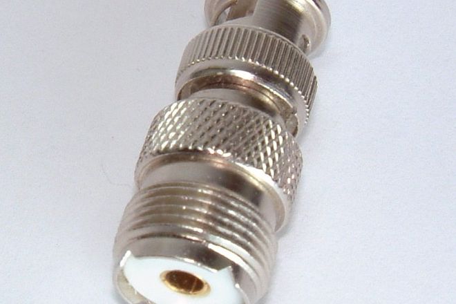 A BNC-to-UHF adapter showing its SO-239 socket end: a threaded barrel filled with white insulator around a centre hole
