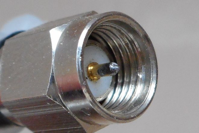An SMA plug on the end of a coaxial cable: a hex nut around a white insulator with a fine centre pin