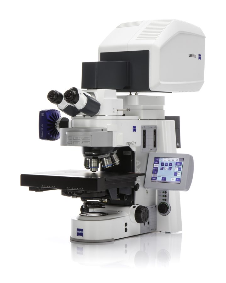 A white laboratory microscope with a large laser scanning unit mounted on top, a motorised stage and a touch-screen control panel