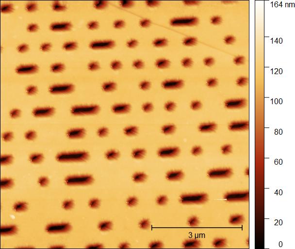An atomic force microscope image of a DVD's recording layer: rows of dark oval marks of different lengths on a light background, with a 3 micrometre scale bar