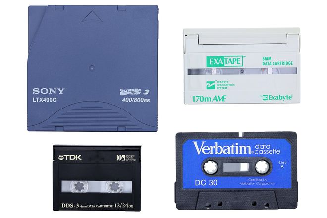 An LTO cartridge beside smaller DDS and other backup tapes