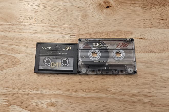 A small DAT cassette beside a larger audio cassette