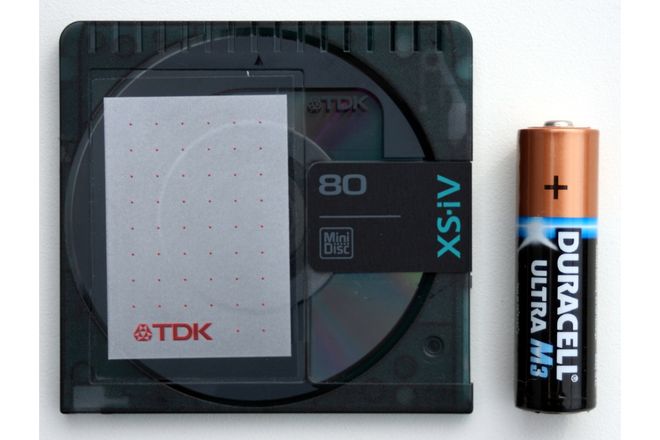 A TDK MiniDisc beside an AA battery for scale